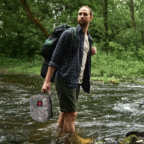 Man crossing stream holding 125 In 1 All In One Survival Kit For Men Outdoor Gear With First Aid Supplies Emergency SOS Tactical Tools