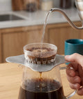 Total Game Changer Metal Coffee Drip Assist Tool And Portable Pour Over Dripper Stand with hot water pouring into filter.