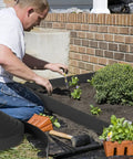 Man installing 2 Inch Landscape Edging Kit with 3 Rolls Spanning 354 Feet and 324 Anchoring Spikes Flexible Border Edge for Flower Bed