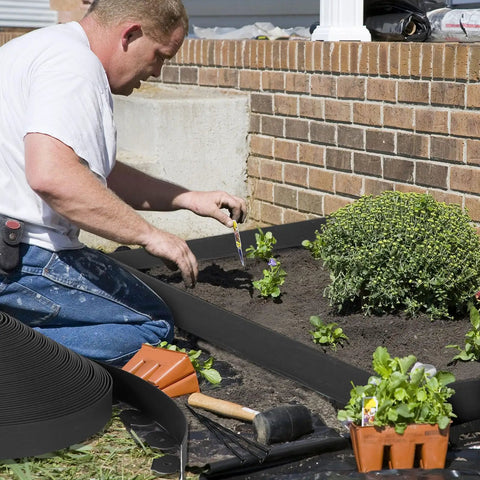 Man installing 2 Inch Landscape Edging Kit with 3 Rolls Spanning 354 Feet and 324 Anchoring Spikes Flexible Border Edge for Flower Bed