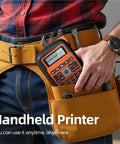 Slick E1000 Pro Handheld Portable Label Printer For Fast Industrial Marking On Multiple Surfaces With Hella Efficient Personalized Adhesive Labels And Boss Level Workspace Organization Tool In Classic Gray, held in tool belt.