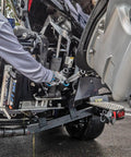 Person installing Motor Stik Pair Heavy Duty 8.75 Inch Transom Saver on outboard motor for trailering on wet pavement.