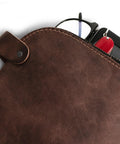 Close-up of Rugged Leather Dopp Kit For Cords And Chargers with keys and glasses peeking out, bourbon brown leather texture.