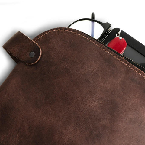 Close-up of Rugged Leather Dopp Kit For Cords And Chargers with keys and glasses peeking out, bourbon brown leather texture.