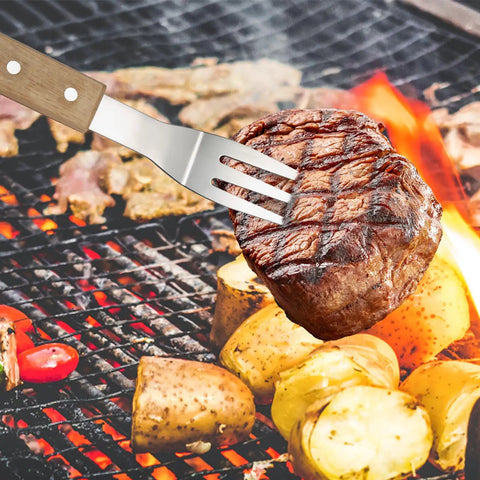 4 Piece Stainless Steel BBQ Grill Utensil Set With Wood Handles meat fork holding steak over grill with vegetables
