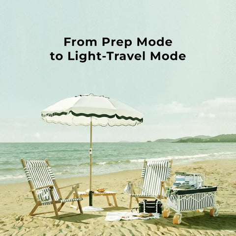 Foldable Beach Wagon With Six Point Seven Inch Fat Tires For Sand And Mixed Terrain next to striped chairs and umbrella on beach