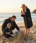 Family wearing Mens Waterproof Swim Parka With Hooded Poncho For Beach Or Pool building sandcastles, showcasing oversized coats