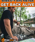 Person sitting by a lake with survival gear, wearing a Paracord Survival Bracelet 2 Pack With Fire Starter Ferro Rod Loud Whistle Compass.