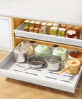 Make Kitchen Storage A Cinch With This Expandable Pull Out Organizer featuring organized pots in a white slide out drawer.