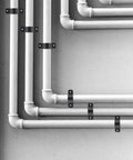Front view of black metal pipe support clamps securing white PVC/PEX pipes to a wall; several clamps visible.