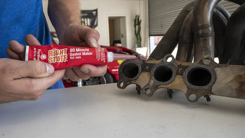 Close-up of a red Permatex Right Stuff gasket maker tube (3 oz) applying to an exhaust manifold gasket