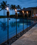 55 Inch Outdoor Oil Torch Lamps Four Pack Rustproof Stainless Steel Citronella Torches by a pool in a backyard setting at night