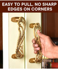 Hand holding peacock decorative brass door handles on interior door.