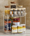 2 Tier Lazy Susan Turntable Organizer For Narrow Cabinets with jars and spices, clear plastic, placed in a kitchen corner.