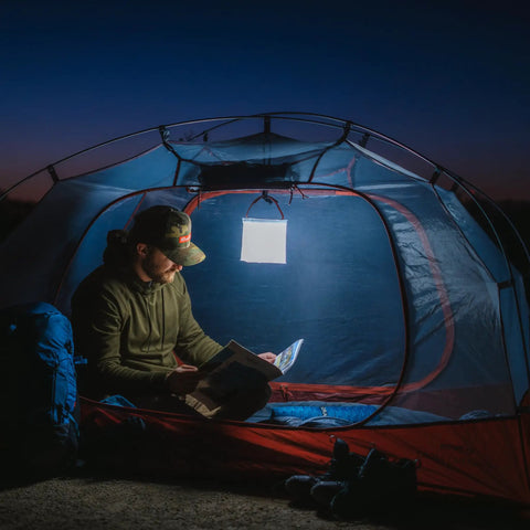 Camper reading in tent illuminated by Your Go To Quick Inflate 2 In 1 Solar Lantern And Phone Charger For Camping Hiking And Travel Rechargeable LED Light