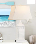 Coastal White Resin Table Lamp with USB A to C Outlet in living room setting, featuring seashell details and beige lampshade.