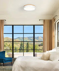 Bright bedroom with large windows, a blue chair, and a white ceiling light against a mountain backdrop