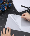 Person handling Rhinestone Transfer Sheets 27 Ft By 9 In Film Paper Hot Fix Tape for DIY positioning on fabric, 0.3mm thick.