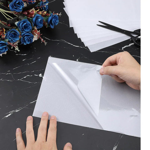 Person handling Rhinestone Transfer Sheets 27 Ft By 9 In Film Paper Hot Fix Tape for DIY positioning on fabric, 0.3mm thick.