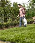 Man using 2 Gallon Lawn And Garden Sprayer For Controlling Insects And Weeds Or Cleaning Decks And Siding with comfort grip outdoors.
