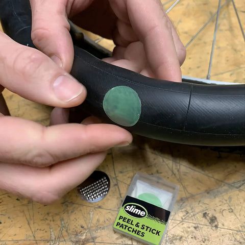 Applying peel and stick patch on bike tire from Bike Tire Patch Kit With Peel And Stick Patches And Extra Tough Tire Levers.
