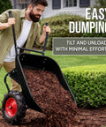 Man using Heavy Duty Dual Wheel Workhorse Wheelbarrow Garden Cart With 500 Lb Capacity Extra Large Wheels Built In Stand Jet Black