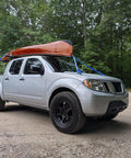 Truck with kayak secured using Heavy Duty 1 Inch Ratchet Tie Down Strap 6 Ft Long, 900 Lbs Break Strength, in wooded area