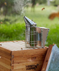 Pro Grade Beehive Smoker With Stainless Steel Body And Heat Shield for hive inspections on wooden bee box outdoors