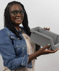 Person holding medium plastic storage bin, stackable clear organizer container with open front design for easy access