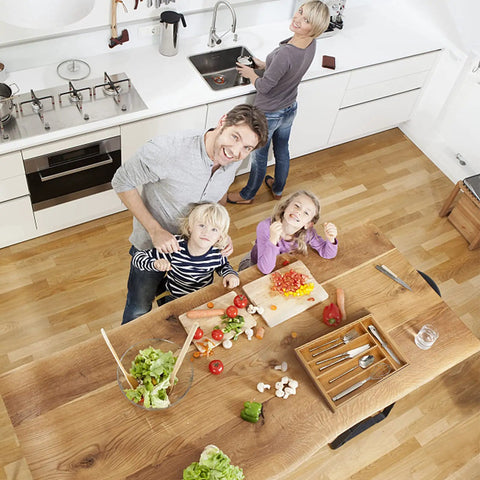 Family preparing meal in kitchen with Expandable Bamboo Kitchen Drawer Organizer For Cutlery And Utensils on table.