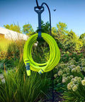 Garden Hose Kit With Quick Connect Attachments Lightweight Flexible Half Inch By Fifty Foot Hybrid Polymer Hose That Coils Easily Includes Twist Nozzle Flow Stop Coupler Spigot Adapter Hose Adapters And Hose Hanger Will Not Kink Under Pressure, hanging in garden.