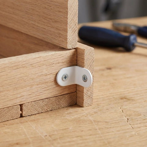 Close-up of a Beefy Heavy Duty 24 Piece Stainless Steel L Bracket Corner Brace securing a wood joint at a 90-degree angle with screws.