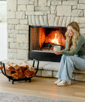 Curved 24.5 Inch Firewood Rack With Kindling Hooks For Indoor And Outdoor Use beside a lit stone fireplace