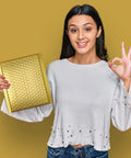 Smiling woman holding a Gold Bubble Mailers 6x10 For Jewelry And Makeup Supplies 50 Pack Metallic Envelope against a gold background.