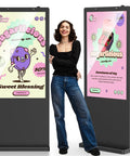 High Octane Outdoor Floor Standing Digital Signage Display Features A Rust Proof Galvanized Steel Chassis With Shatter Resistant Glass Plus Rock Solid Wifi Hdmi Usb Ports Running Smooth Android Apps Built To Crush Busy Retail Stores Subway Lines And next to a woman promoting candy shop deals.