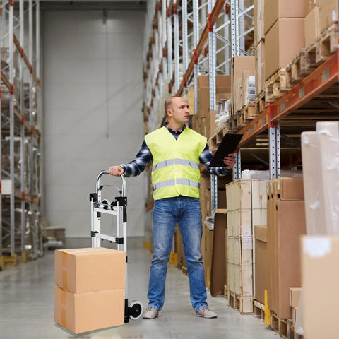 Man using Heavy Duty 600 Lb Hand Truck Featuring Rock Solid Build in a warehouse to transport cardboard boxes.