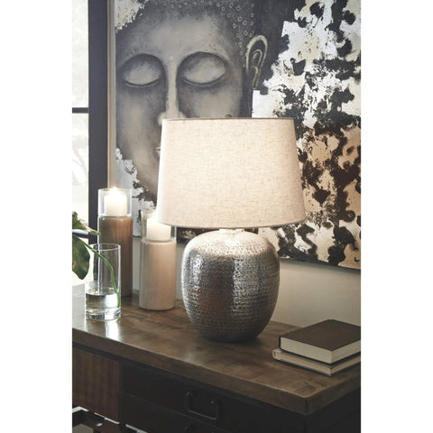Magalie Contemporary Table Lamp In Antique Silver With Hammered Aluminum Construction on table with books and candles.