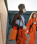 Two people wearing masks and orange suits with knapsack sprayers, illustrating use of Gallon Sprayer Barrel Mouth Filter.
