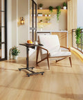 Must-Have Adjustable Overbed Table With 180-Degree Swivel Desktop beside a chair in a modern living room with plants.