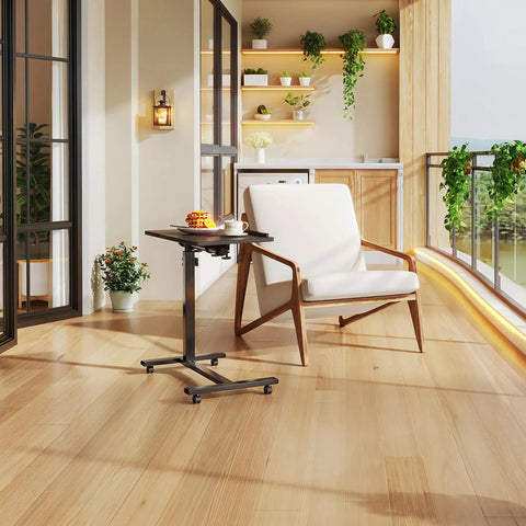 Must-Have Adjustable Overbed Table With 180-Degree Swivel Desktop beside a chair in a modern living room with plants.