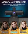 4K Auto Focus USB Web Cam With Dual Mics And Quick Privacy Flip Hella Crisp Video For Seamless Meetings Live Streams And Streamer Clips Plug And Play On PC Or Laptop A Total No Brainer Purchase showing low-light correction feature and user smiling in a yellow sweater.