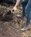 Person using Beast Survival Folding Camp Shovel With Pickaxe Tri Fold Tactical Entrenching Tool for digging in dirt outdoors.