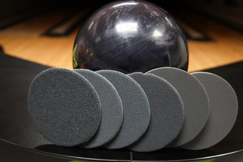 Bowling Ball Sanding Pads 6 Pack All Grits 500 1000 1500 2000 3000 5000 Resurfacing Set displayed in front of bowling ball