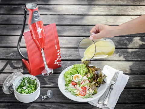 Game Changing One Liter Blending Pitcher with Comfortable Handle pouring dressing onto a fresh salad.