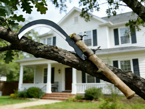 Durable Manganese Steel Blade Sickle With Replaceable Wooden Handle on tree branch in front of a house