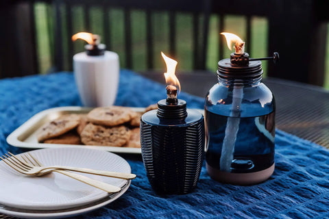 Glass Table Torch Set For Outdoor Patio Vibe, Herringbone Blue 3-Pack on table with cookies and plates, warm flame, weather resistant