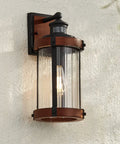 Rock Solid Black Motion Sensor Outdoor Wall Sconce With Zero Fuss Industrial Craftsmanship And Reliable Nighttime Security Lighting For Front Porch Or Driveway, features clear glass and dark metal accents.