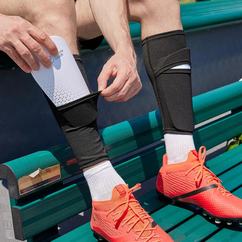 Person inserting shin guard into Soccer Shin Guard Sleeves With Insert Pocket And Top Lid, Breathable Mesh, Size Large, Black.