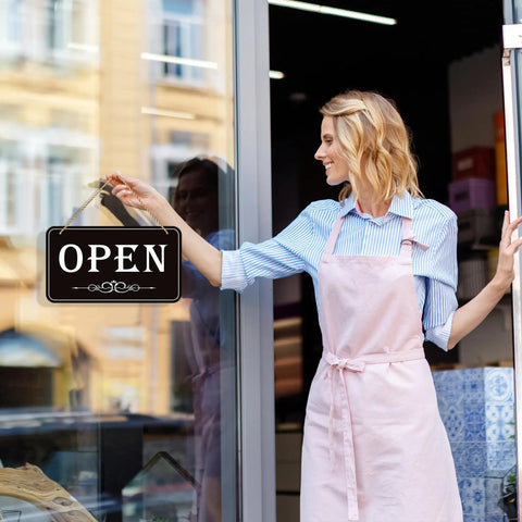 Person hanging an Open Closed Sign For Biz 12x6.7 Inches Waterproof Double Sided Hanging Sign That Says Come In Or Closed With Hours Flip for Stores.