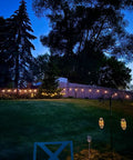 Solar Powered Outdoor String Lights 48 Ft Commercial Grade Waterproof Patio Lights With 15 Shatterproof LED Edison Bulbs glowing in a backyard at night.